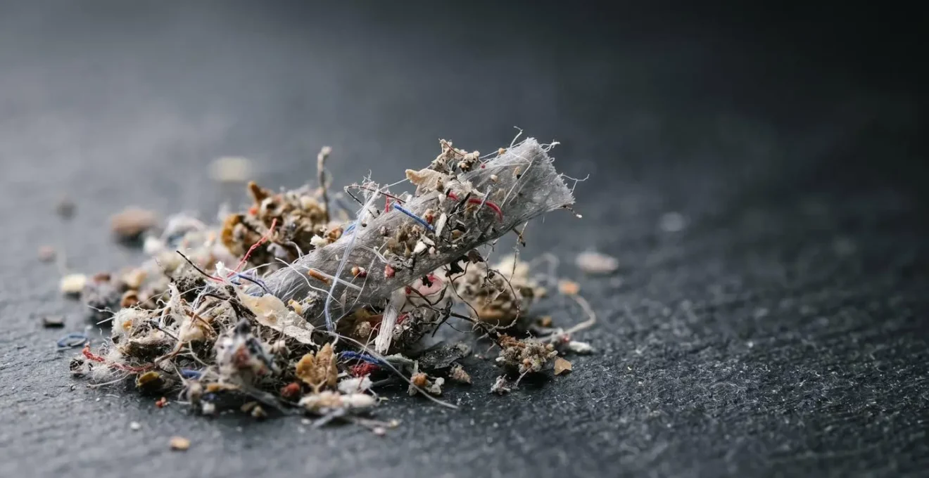 Extreme close-up macro photograph revealing the textural complexity of household dust particles and fibers