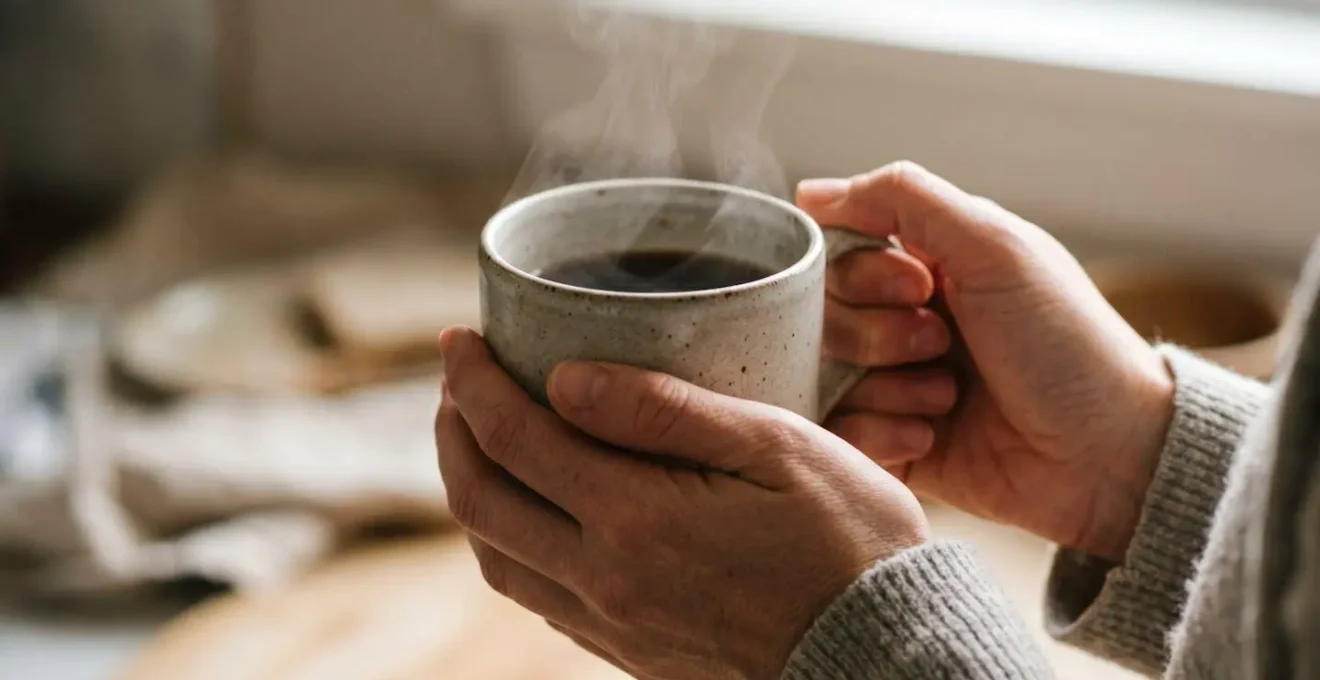 Hands gently holding warm beverage in moment of intentional pause