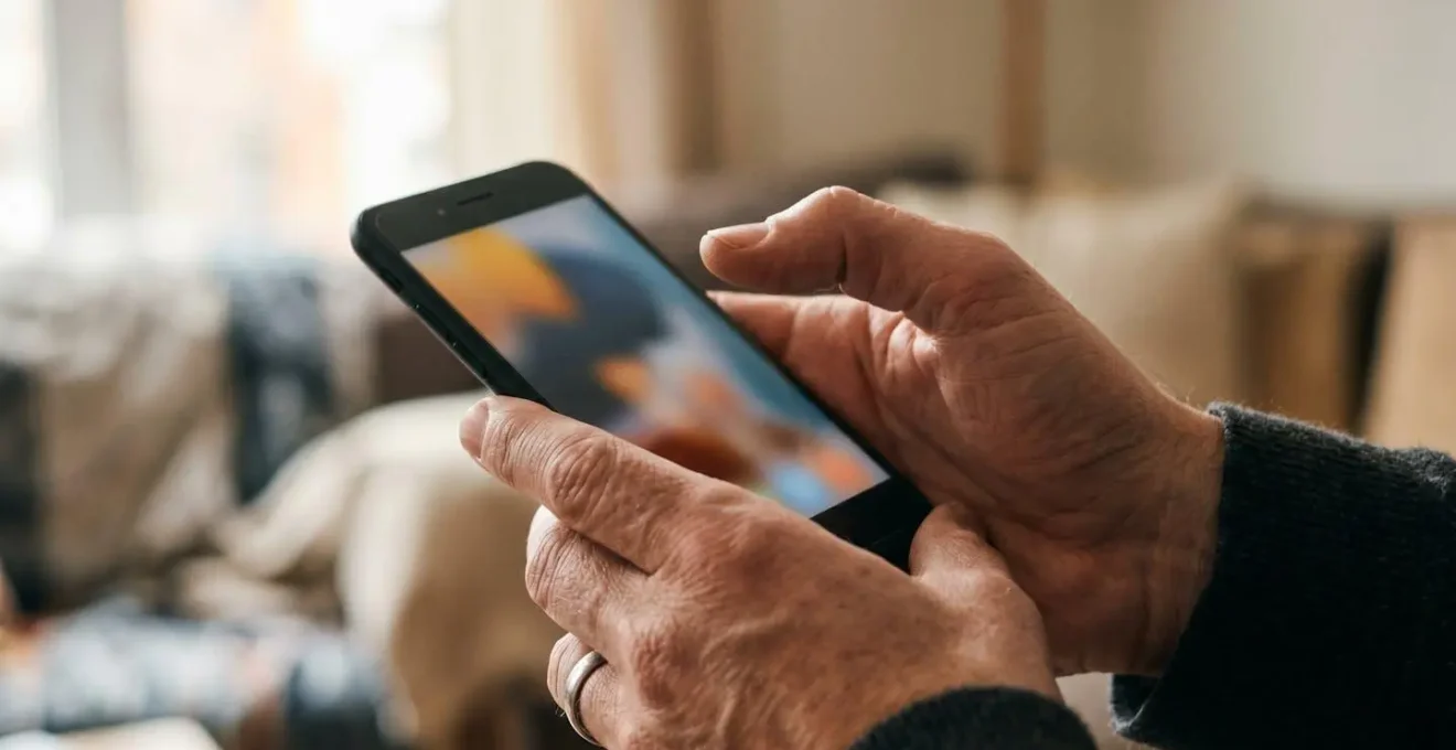 Close-up of hands holding a smartphone showing the ended call screen, with soft natural window light casting a gentle glow, conveying emotional tension.