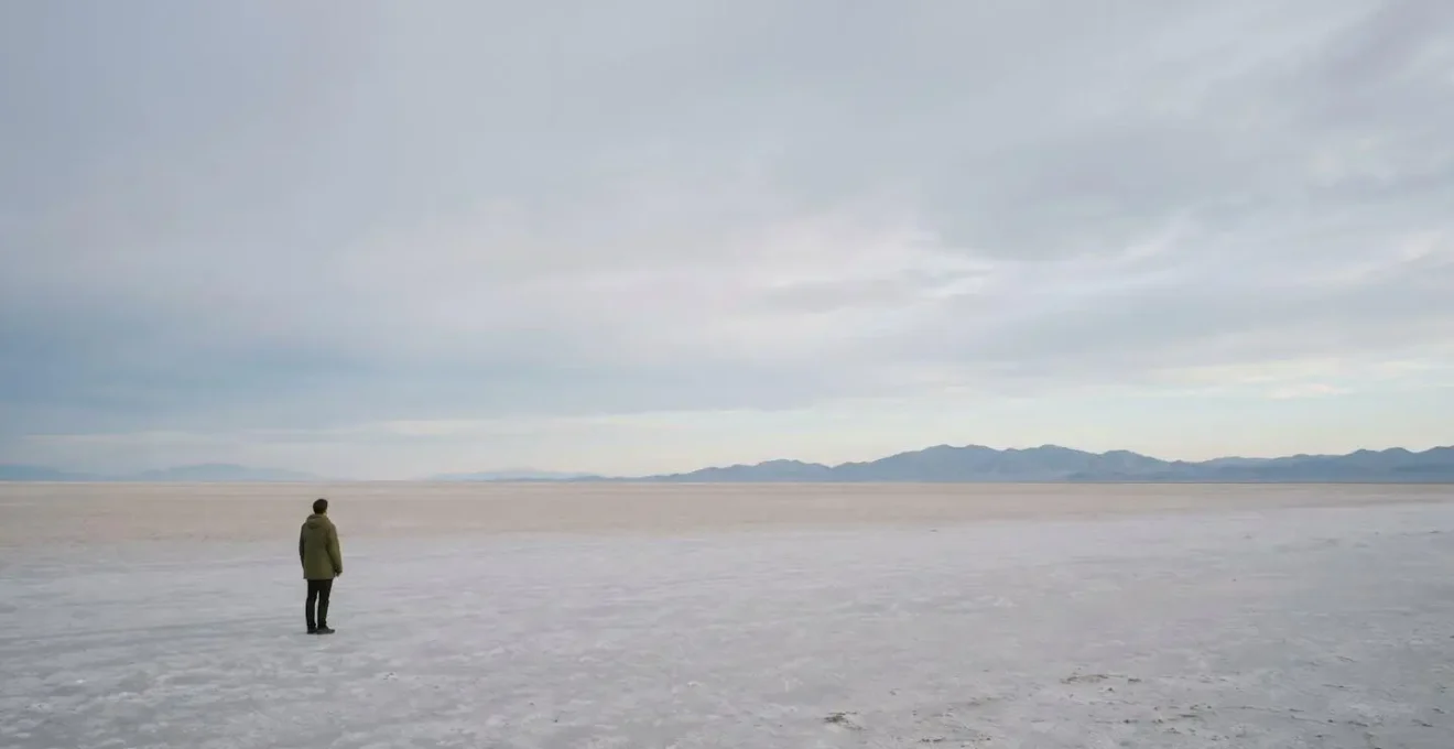 A serene, vast landscape with a small figure, representing the mental distance of observing thoughts.